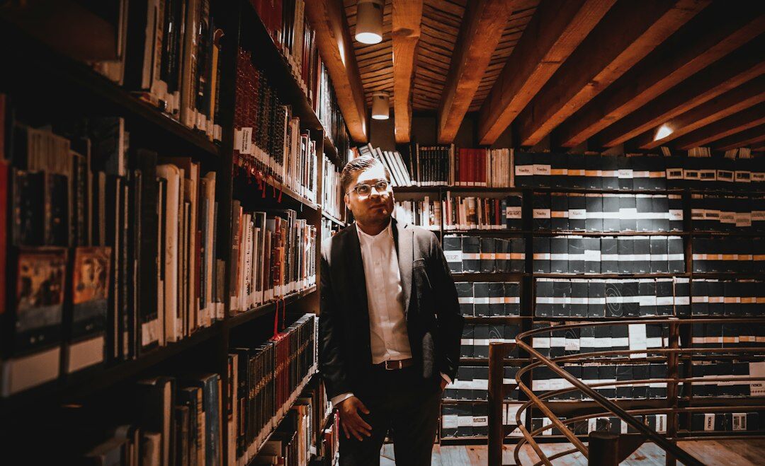 Croatian male writer standing among bookshelves in his home library