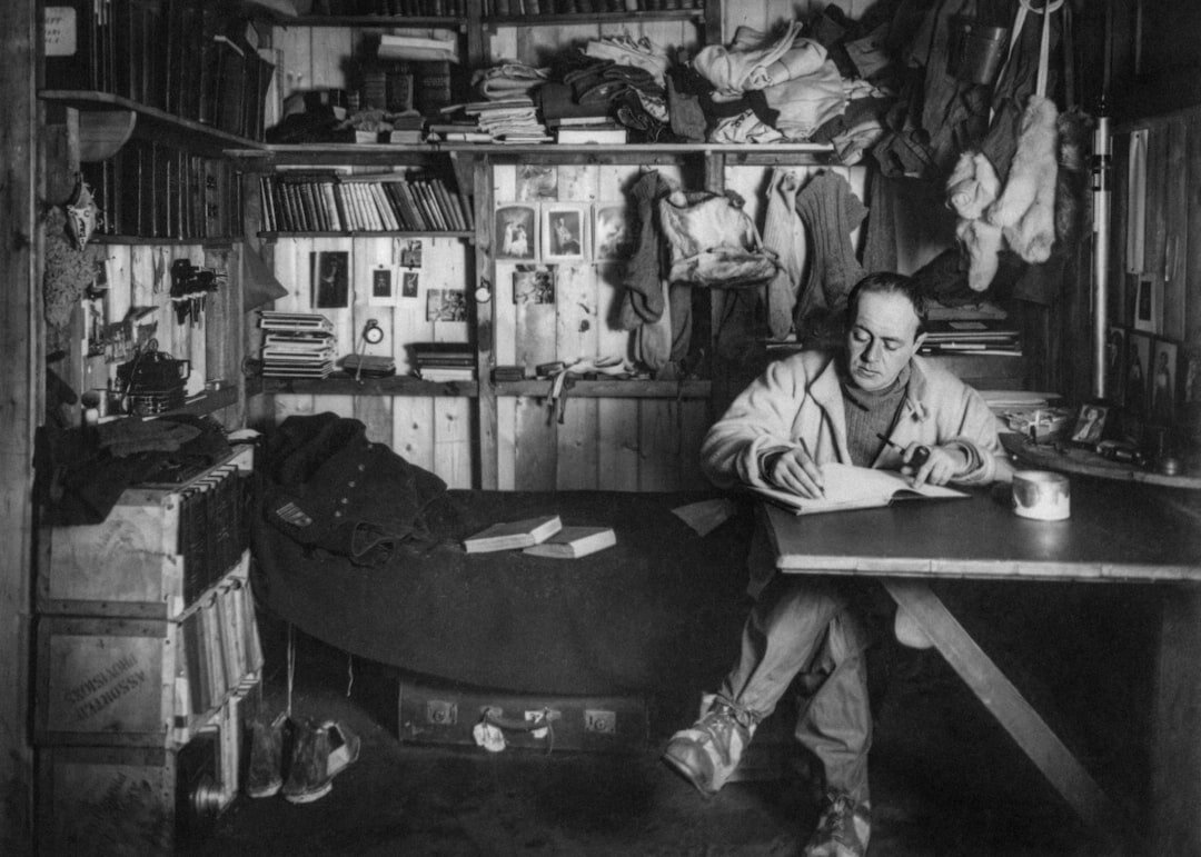 Croatian male writer sitting at a wooden desk writing by hand in a notebook
